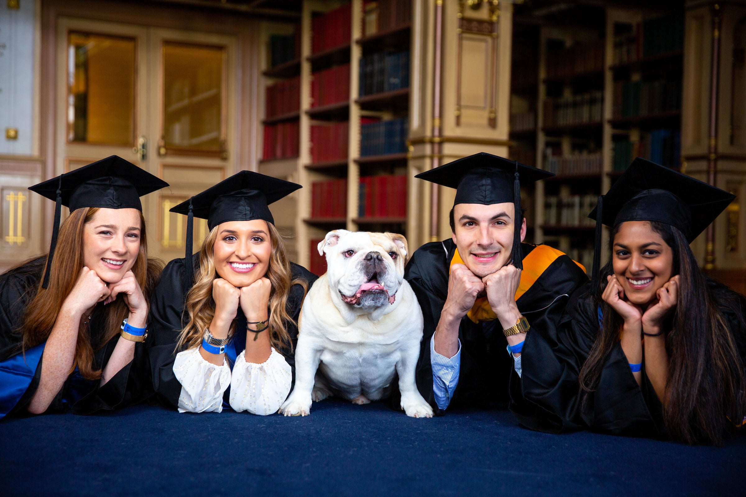 students in graduation caps posing with Jack the Bulldog